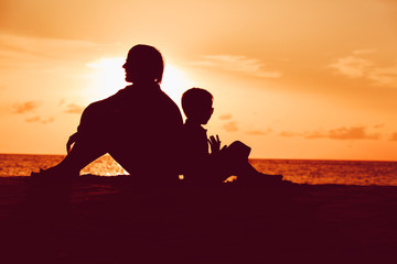 father and little son looking at sunset on beach