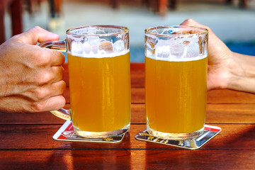 Male and female hands clink mugs with beer
