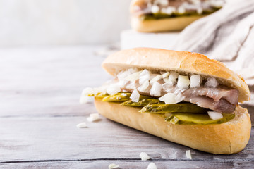 Traditional dutch snack, seafood sandwich with herring, onions and pickled cucumber. Broodje haring. Copy space.
