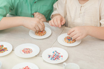 Cute children decorate cookies at a table in the home kitchen