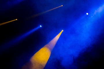 The blue-yellow light from the spotlights through the smoke in the theatre during the performance....