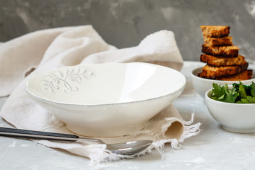 Empty plate for soup, the table is served for dinner, parsley and croutons in the bowls.