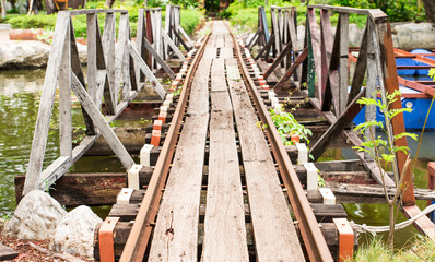 Small railroad tracks made of steel and wood build a bridge over the water canal.