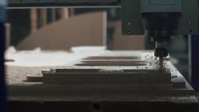Automatic milling cutting wood machine.  drill holes for the pieces of wood. Closeup. Slowmotion. Sawdust fly in different directions