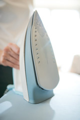 Female tailor with iron on ironing board