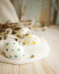 Easter eggs with spring branches of a willow on a wooden background.