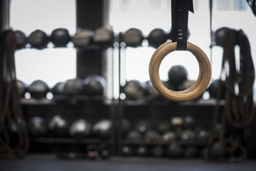 Fototapeta na wymiar Closeup of gymnastic rings in gym with blurred equipment in background