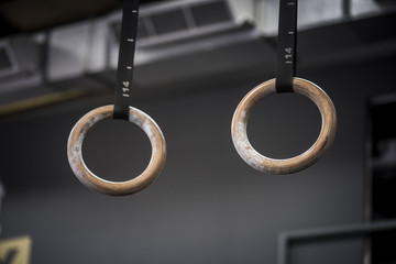 Closeup of gymnastic rings in gym with blurred athlete in background