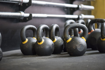 Naklejka na ściany i meble Large grouping of kettlebells and barbells in a cross fit gym with a blurred background