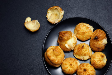 Profiteroles eclairs on black matte plate.Top view .Copy space