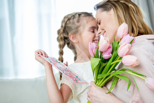 happy mother hugging daughter with postcard on mother's day