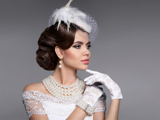 Retro woman portrait. Elegant lady with hairstyle, pearls jewelry set wears in hat and lace gloves...