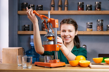 Beautiful woman making detox juice from orange with juicer