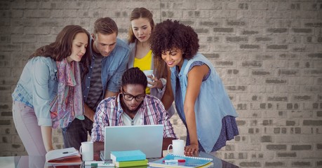 Composite image of People around laptop against brick wall