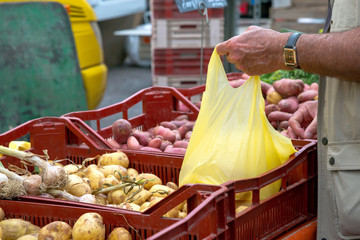 man buying new potatoes from local market