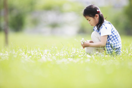 Girl Sitting on Grass Surrounded By Flowers