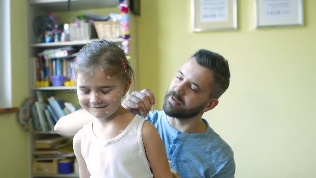 Little girl with chickenpox, father applying antiseptic cream to rash