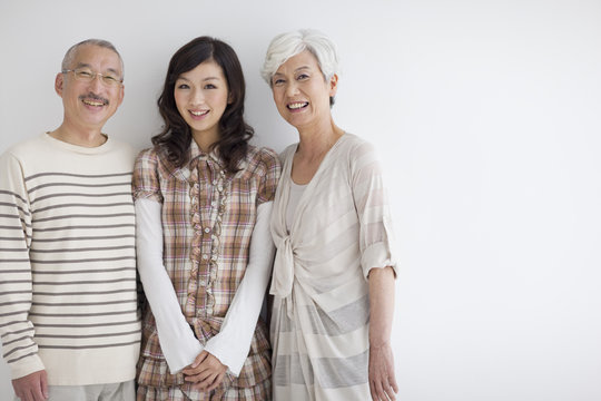 Portrait of family standing side by side, smiling, white background, copy space