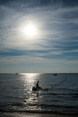 Silhouette of surfer man siting on surfboard in sea