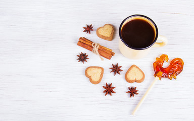 Naklejka na ściany i meble Black coffee with spices and sweets on a white wooden background. Coffee, biscuits and lollipop.