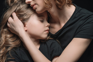 portrait of stylish daughter and mother hugging on black