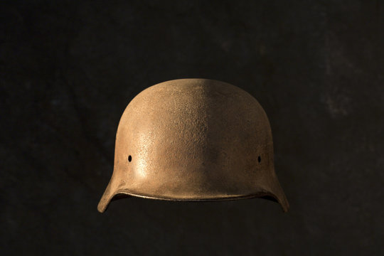 A rusty German World War Two military helmet, on black background