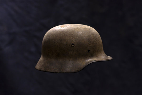 A rusty German World War Two military helmet on dark background