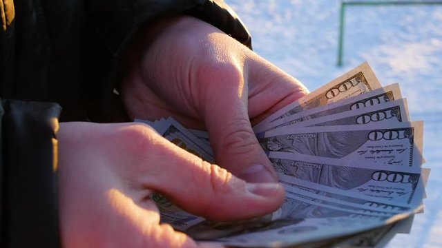 the guy counts the money in hand outdoors