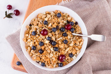 Bowl of homemade granola with fresh berries on white background from top view