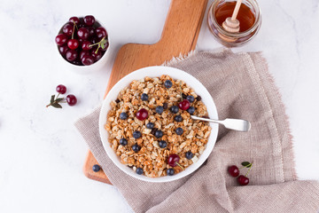 Bowl of homemade granola with fresh berries on white background from top view