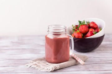 Strawberry smoothie or milkshake in jar on white wooden rustic background