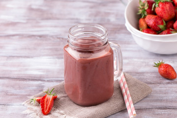 Strawberry smoothie or milkshake in jar on white wooden rustic background