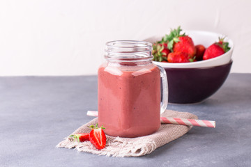 Strawberry smoothie or milkshake in jar on gray rustic background.