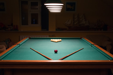Billiard table with balls and cues in the light of the lamps
