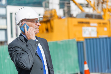 Man architector outdoor at construction area having mobile conversation