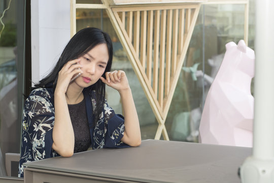Asian woman is serious when calling business line by smartphone