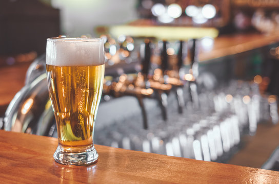 Glass of Beer on a bar table. Beer Tap on background