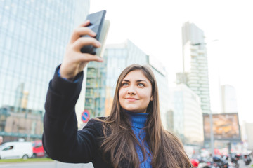 Young beautiful eastern woman outdoor in the city taking selfie using smart phone - vanity, social network, communication concept