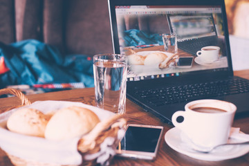 A cup of coffee and breakfast, a laptop computer in a modern cafe bar.