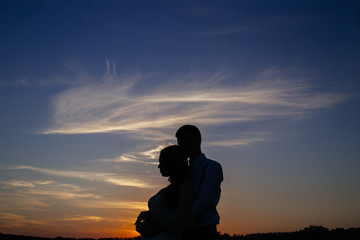 Fototapeta na wymiar Silhouettes of a loving couple hugging at sunset