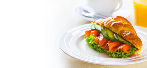 croissant sandwich with salmon and avocado, coffee and orange juice on a white background