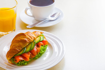 croissant sandwich with salmon and avocado, coffee and orange juice on a white background