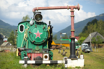 An old rusty locomotive with a red Soviet star stands on an abandoned railway station as a symbol of the collapse of communism