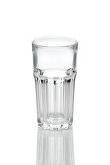 Empty transparent faceted glass with reflection on white background.
