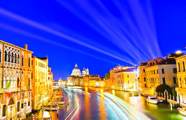 View of the Grand Canal in Venice at night with laser light projected into the sky. 