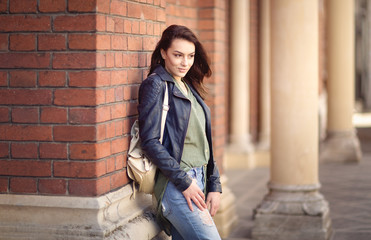 Young woman sitting against the wall. On the streets of town