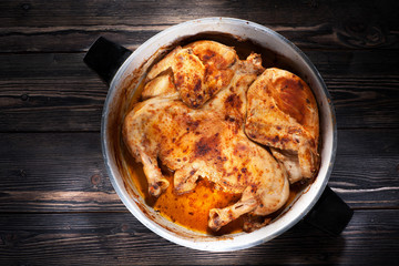 Roasted сhicken tabaka in frying pan on wooden background