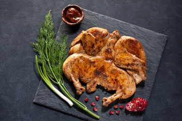 Grilled Roasted сhicken tabaka on a black stone board