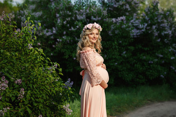 Fototapeta premium Portrait of beautiful pregnant woman in spring or summer park