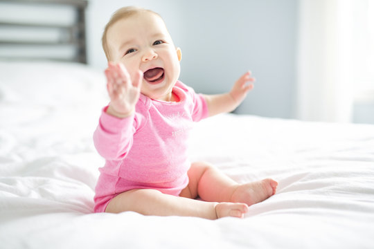 baby girl sit on white sheet